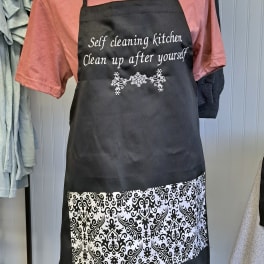 Black apron with white text over a pink shirt