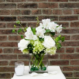 White roses and alstroemeria in a square glass vase with green hydrangea
