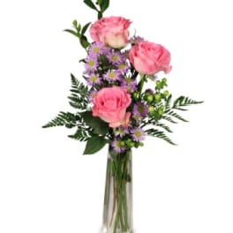 Pink roses and purple daisies in a tall glass vase