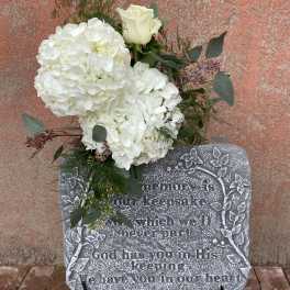White floral spray on a memorial stone with a single white rose