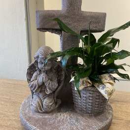 Potted green plant beside a stone cross and angel statue