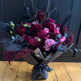 Bouquet of dark red and pink flowers wrapped in black paper