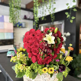 Red rose arrangement in a rustic rectangular box with mixed accent flowers