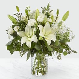 White lilies and roses arranged in a clear glass vase