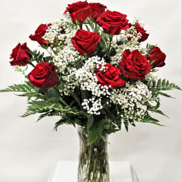 Arrangement of red roses with white filler flowers in a clear glass vase