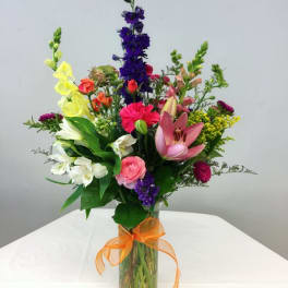 Colorful mixed bouquet in a glass vase with an orange ribbon