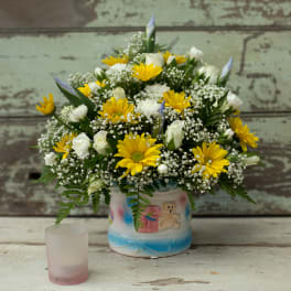 Yellow daisies and white roses arranged in a decorated ceramic vase
