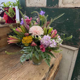 Mixed bouquet in a clear glass vase with pink, purple, and yellow blooms