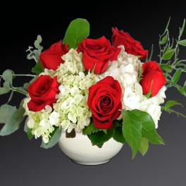 Red roses and white hydrangeas in a white bowl vase