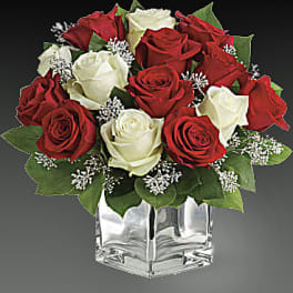 Red and white roses arranged in a clear square vase