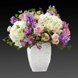 Pink and purple flowers arranged in a white vase