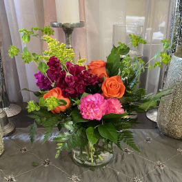 Mixed bouquet of orange and pink flowers in a clear glass vase