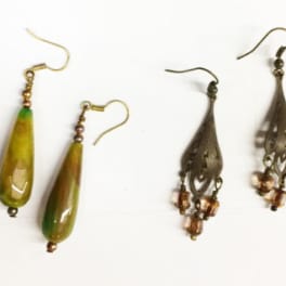 Pair of green teardrop earrings and pair of dark beaded earrings on a white background