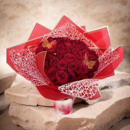 Bouquet of red roses wrapped in red paper with white mesh accents