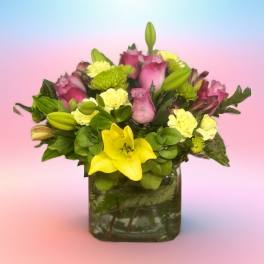 Bouquet of pink roses, yellow lilies, and green mums in a glass vase