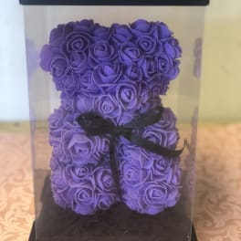Purple rose-shaped teddy bear in a clear gift box with a black ribbon
