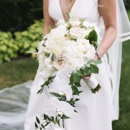 Bride holding a white bouquet with cascading orchids and roses