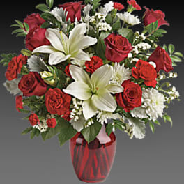 Red roses and white lilies arranged in a red glass vase