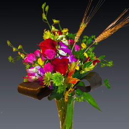 Mixed bouquet of red, pink, and purple flowers in a clear glass vase