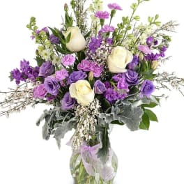 Purple and white bouquet in a clear glass vase with a lavender ribbon