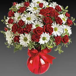 Red roses and white daisies in a red vase with a ribbon