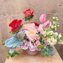 Pink and red floral arrangement in a textured vase