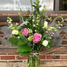 Pink roses and white blooms arranged in a glass vase