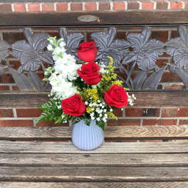Red roses and white flowers in a white vase
