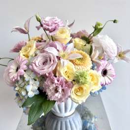 Pastel bouquet of roses, daisies, hydrangea, and lisianthus in a white vase