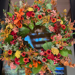 Autumn wreath with orange, red, and yellow flowers on a dark door
