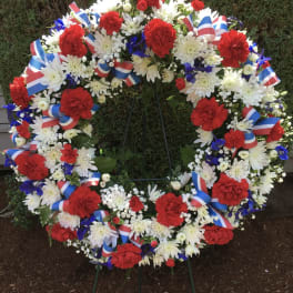 Large patriotic floral wreath with red, white, and blue flowers on a stand