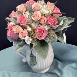 Pink and peach roses arranged in a white ceramic pitcher