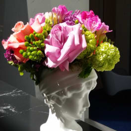Pink and coral roses with green hydrangeas in a white bust vase