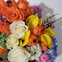 Bouquet of orange and white roses with yellow calla lilies and purple flowers