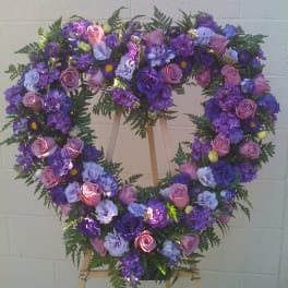 Heart-shaped floral wreath with pink and purple flowers on an easel