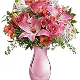 Pink roses and lilies arranged in a pink glass vase