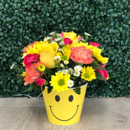 Bright mixed bouquet in a yellow smiley-face container