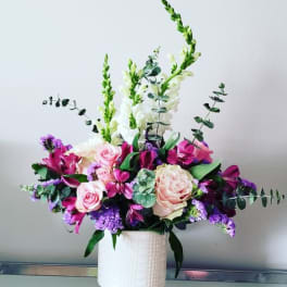 Pink and purple floral arrangement in a white vase