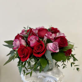 Bouquet of red and pink roses with greenery in a clear vase