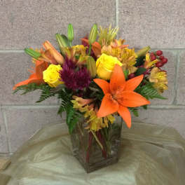 Mixed bouquet of lilies, roses, and alstroemeria in a glass vase