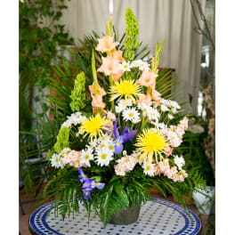 Tall mixed floral arrangement in a vase with yellow, white, peach, and purple blooms