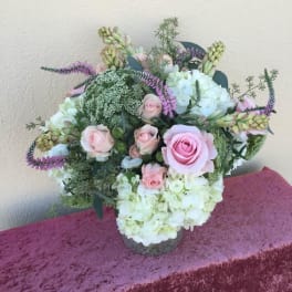 Pink roses and white hydrangeas arranged in a low vase.