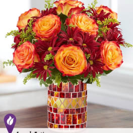 Orange roses and burgundy daisies in a mosaic glass vase