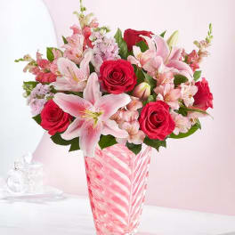 Pink lilies and red roses in a striped glass vase