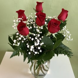 Red roses with white baby's breath in a clear glass vase
