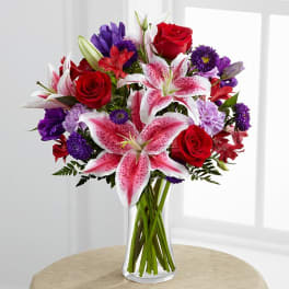 Bouquet of red roses and pink lilies in a clear glass vase
