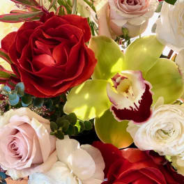 Bouquet of red, blush, and white roses with a green orchid