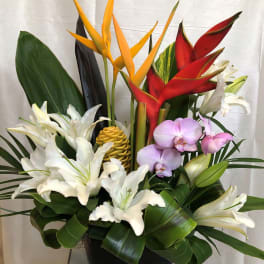 Tropical floral arrangement with white lilies, orchids, and red and yellow heliconia in a black vase