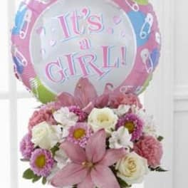 Pink and white flower arrangement with a "It's a Girl!" balloon
