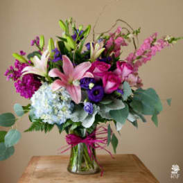 Mixed bouquet of pink, purple, and white flowers in a glass vase